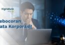 Ilustrasi seorang pebisnis cemas di depan laptop menghadapi ancaman kebocoran data korporasi oleh hacker di samping simbol palu hakim sebagai risiko hukum.