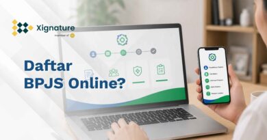 Seseorang sedang mengakses panduan alur pendaftaran BPJS online melalui layar laptop dan aplikasi smartphone di atas meja kerja kantor.