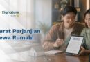 Sepasang pria dan wanita muda tersenyum bersama sambil menunjukkan dokumen kontrak surat perjanjian sewa rumah digital yang sudah ditandatangani di layar tablet.