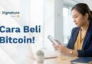 Ponsel menampilkan aplikasi Bitcoin dengan ikon perisai terverifikasi di samping koin emas