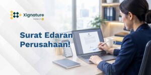 Staf HR menandatangani contoh surat edaran perusahaan secara digital di laptop, dengan ponsel berisi grup chat di sampingnya
