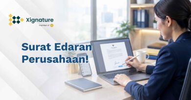 Staf HR menandatangani contoh surat edaran perusahaan secara digital di laptop, dengan ponsel berisi grup chat di sampingnya