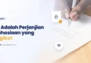 Dua pihak menandatangani perjanjian kerahasiaan (NDA) di atas meja kerja.